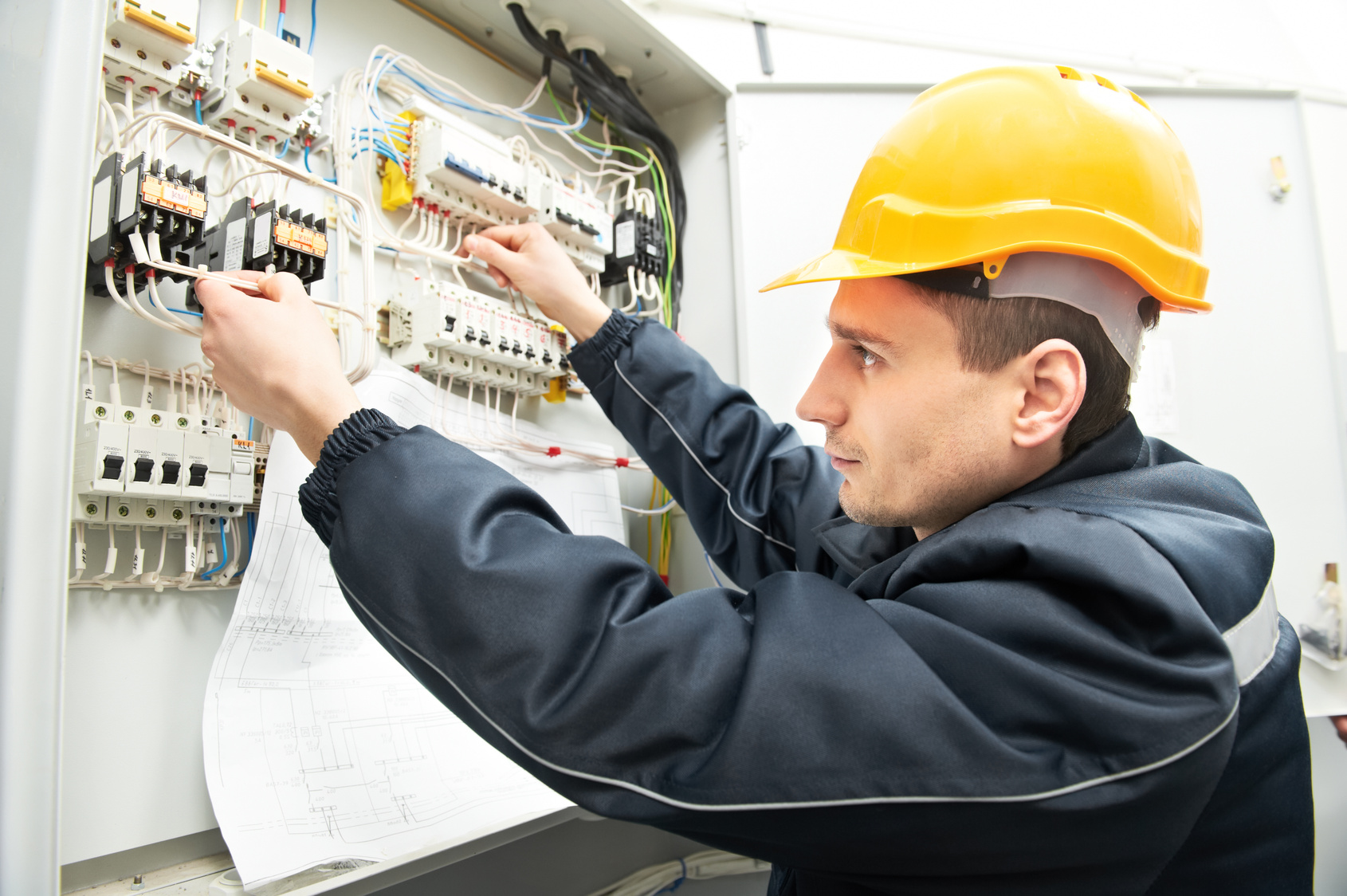 One electrician builder at work with assembly drawing inspecting high voltage power electric line distribution fuseboard
