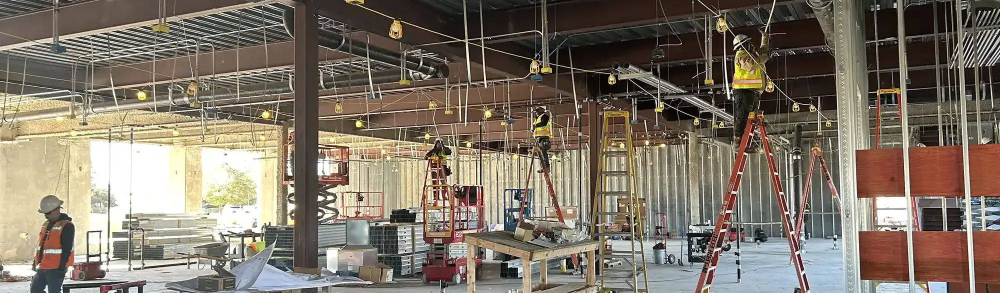 electrical installation work underway inside a large commercial building under construction